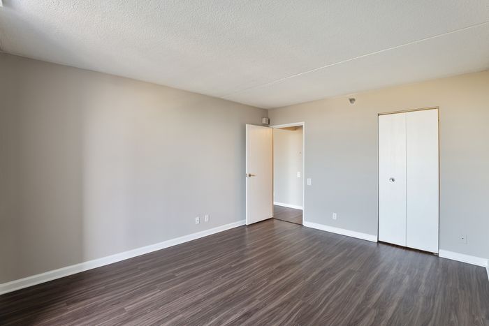 Bright, spacious room with sleek hardwood flooring and modern white doors, perfect for customization and styling.