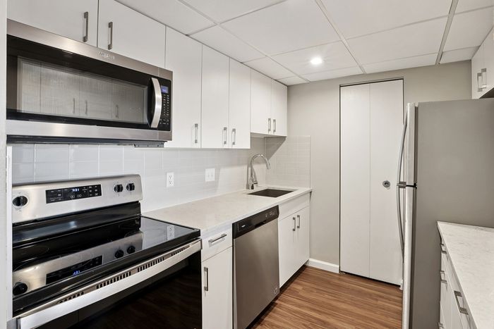 Modern kitchen with sleek stainless steel appliances, glossy white cabinets, and elegant wood flooring, offering a stylish and functional cooking space.