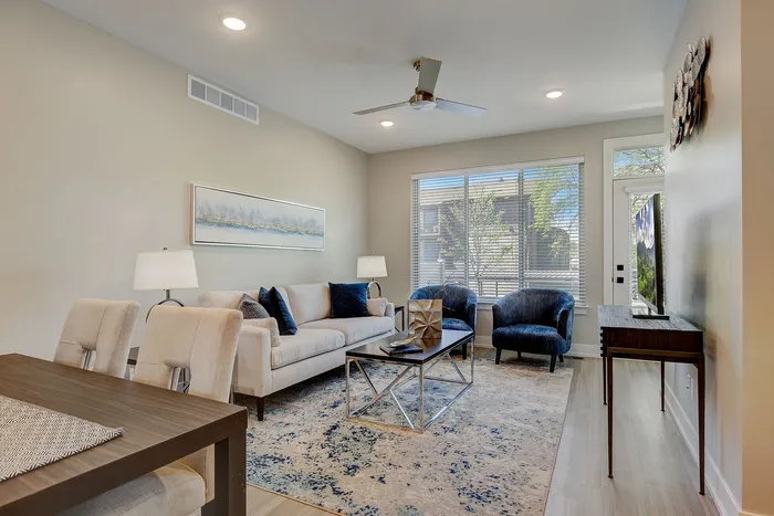 Elegant living room with modern furnishings, featuring a cozy sofa, stylish armchairs, and natural light pouring through large windows for a bright and inviting atmosphere.