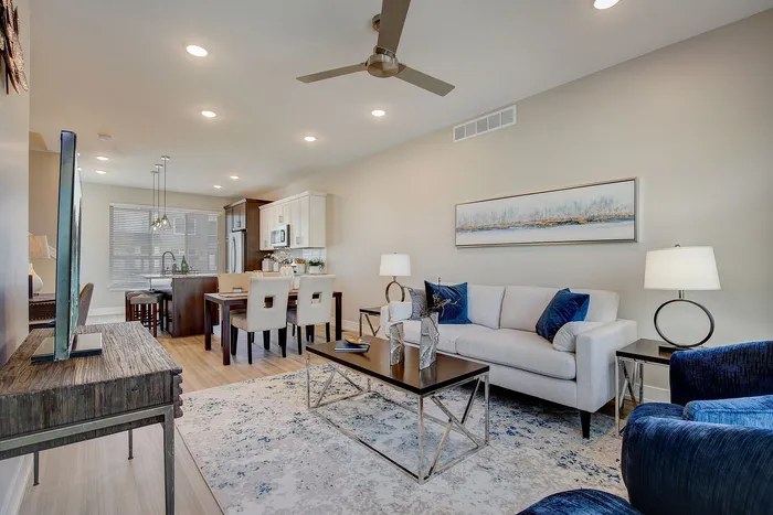 Elegant open-concept living and dining area with modern furnishings, plush seating, and a stylish kitchen backdrop.