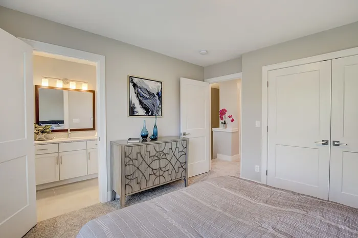Inviting bedroom with modern decor, adjacent bathroom, and artistic accents, offering a serene retreat.