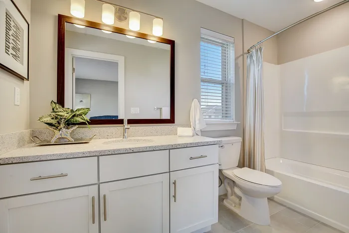 Elegant bathroom featuring a sleek granite countertop, modern fixtures, and ample natural light from a large window.
