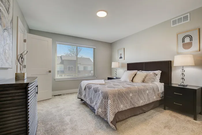 Inviting bedroom with a plush bed and elegant decor, featuring large window for ample natural light.