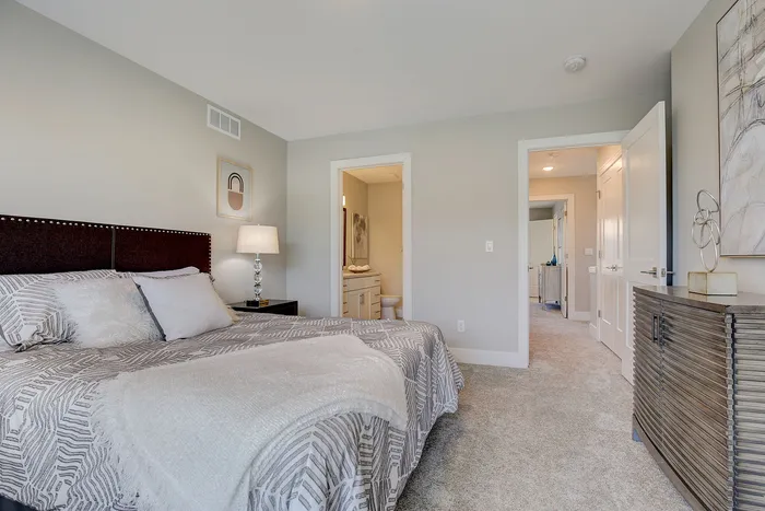 Inviting bedroom with plush bedding, elegant decor, and an en-suite bathroom offering luxury and comfort.