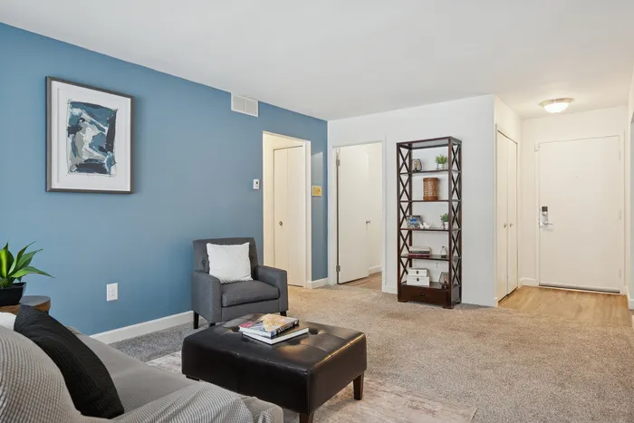 Inviting living room with a modern blue accent wall, cozy armchair, and elegant bookshelf, showcasing a serene ambiance.
