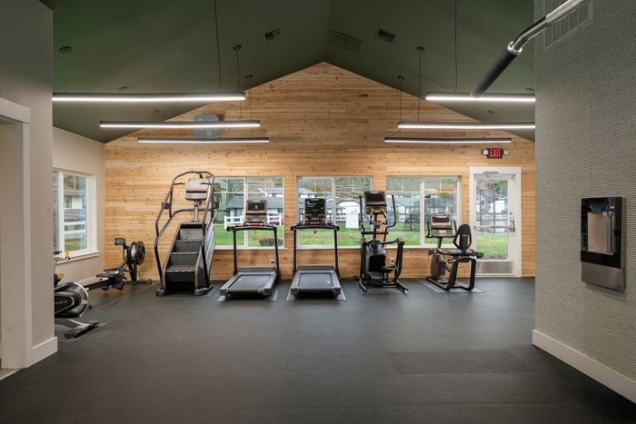 Contemporary fitness center with state-of-the-art exercise equipment, natural wood accents, and large windows offering scenic views.