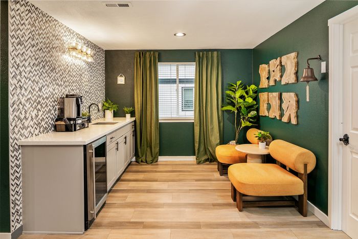 Inviting kitchen nook with chic herringbone backsplash, cozy seating area, and lush green accents for a modern, welcoming vibe.