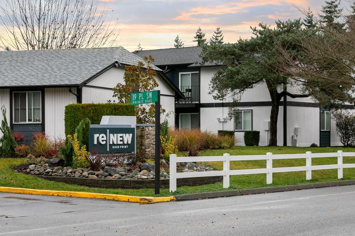Charming entrance to ReNew Dash Point apartments, surrounded by lush greenery and a welcoming landscape.