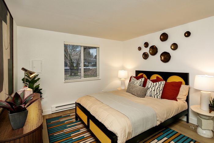 Inviting bedroom with contemporary decor, featuring stylish wall art, abundant natural light, and cozy accents.