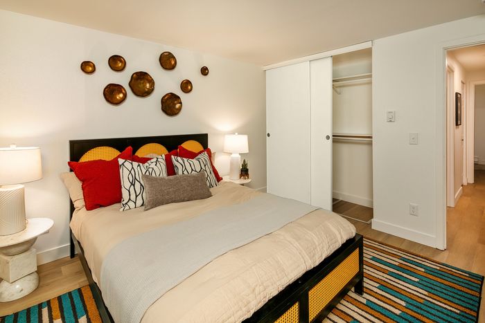 Chic bedroom featuring a cozy bed with vibrant pillows, modern decor, and a spacious closet, perfect for relaxation.