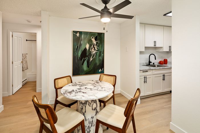Chic dining area with a marble table, modern art, and an elegant kitchen in a bright, inviting apartment space.