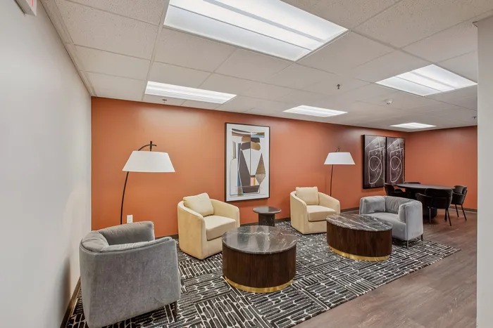 Inviting lounge area with modern chairs, warm orange accent wall, artistic decor, and elegant lighting.