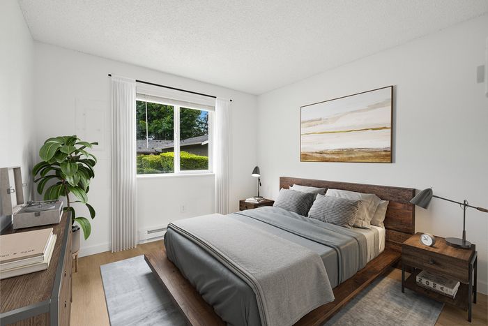 Bright and airy bedroom with a stylish wooden bed frame, modern decor, and a lush view through the window.