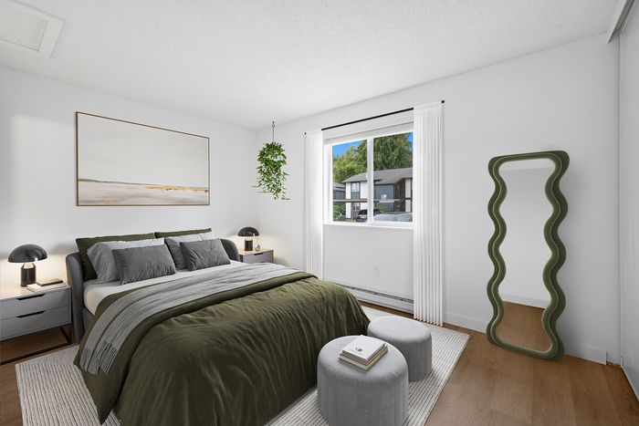 Chic bedroom with modern decor, featuring a plush bed with olive green bedding, stylish art, hanging plant, and full-length mirror. Bright window view enhances the serene atmosphere.