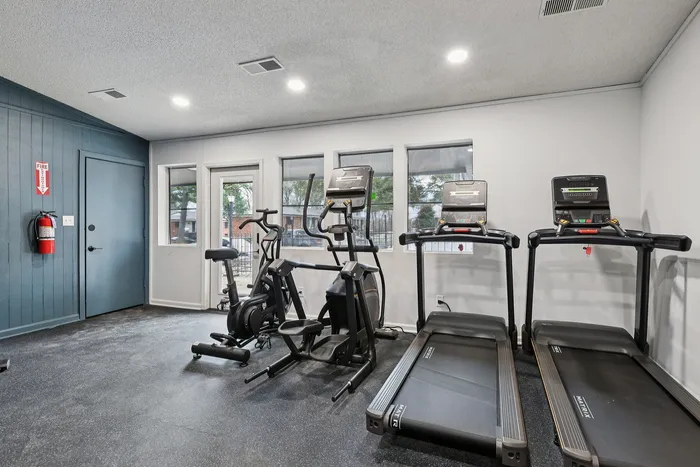 Modern fitness room with advanced machines, including two treadmills and an elliptical, in a bright and inviting space.