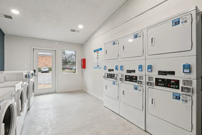 Modern laundry room with washers and dryers, offering bright natural light and a clean, welcoming environment.