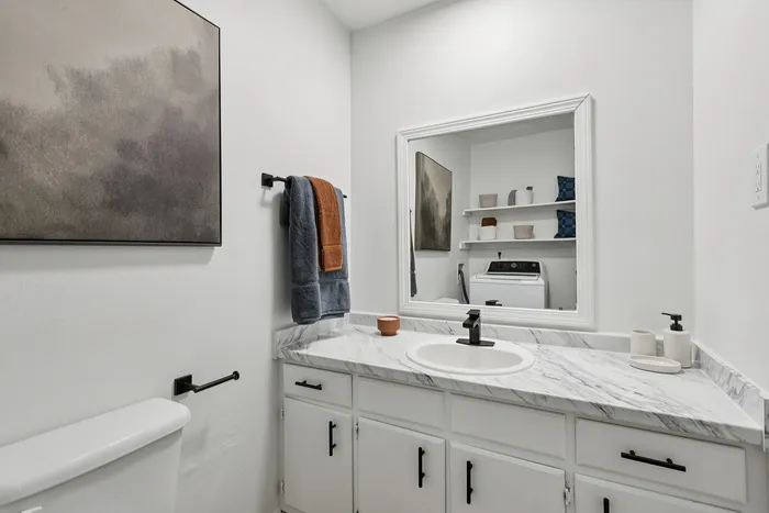 Chic bathroom with modern marble countertop, elegant wall art, and practical laundry space.