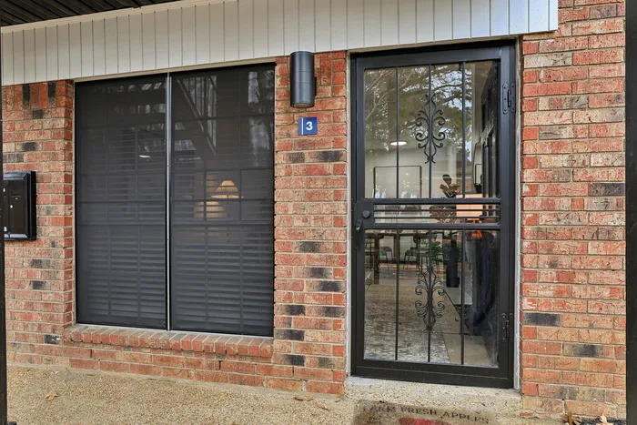 Charming brick exterior with elegant black iron door, featuring a welcoming entrance that offers a glimpse into a cozy interior ambiance.