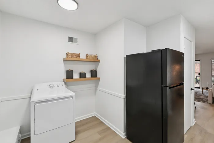 Modern utility area with sleek black appliances, stylish shelving, and bright natural light perfect for any home.