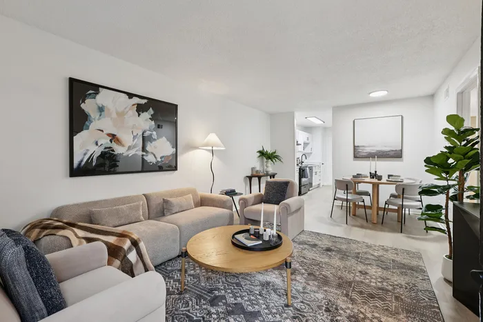 Elegant living and dining area in modern apartment, featuring cozy seating, stylish decor, and an inviting dining table for four.