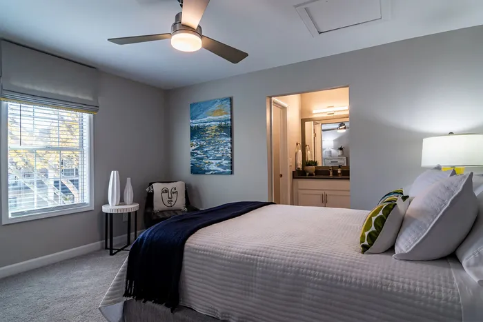 Cozy bedroom with modern decor, featuring a comfortable bed, elegant ceiling fan, and inviting natural light.