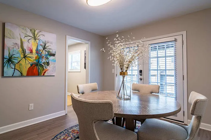 Elegant dining area with plush chairs and artistic decor, featuring a round wooden table and vibrant artwork on the wall.