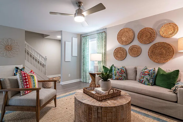 Chic and cozy living room with stylish wicker wall art, vibrant patterned cushions, and a modern ceiling fan, perfect for relaxing.