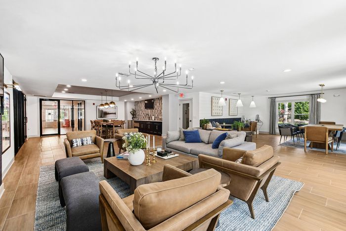 Elegant open-concept living space with modern decor, featuring a cozy seating area, stylish chandelier, and large windows providing ample natural light.