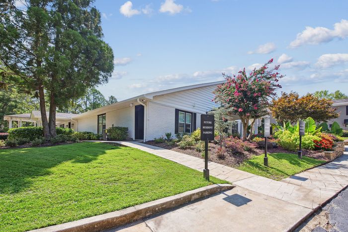 Charming apartment exterior with lush green lawn, vibrant flower beds, and welcoming pathways. Ideal for future residents.