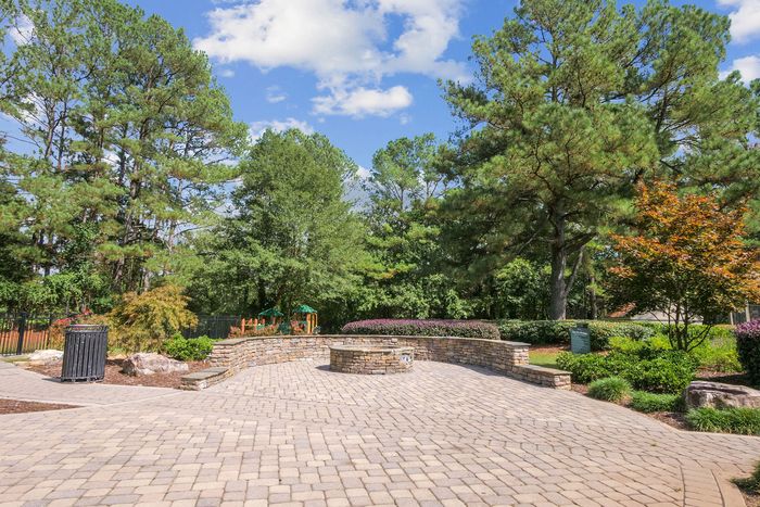 Charming outdoor area with a beautifully landscaped garden, large trees, and a stylish stone-paved patio, perfect for relaxation.