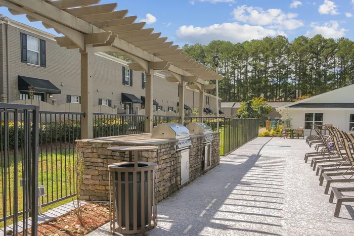 Inviting outdoor area with modern BBQ grills, stylish pergola, and comfortable seating, perfect for entertaining in a serene neighborhood setting.
