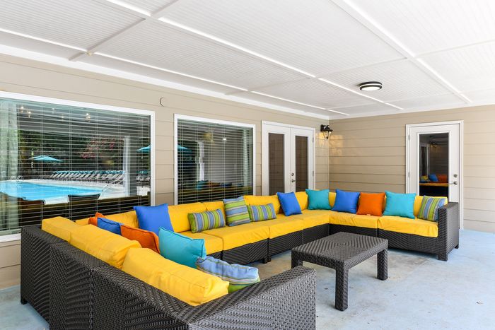 Chic outdoor seating area with vibrant yellow cushions, colorful pillows, and modern wicker furniture, perfect for relaxing by the poolside.