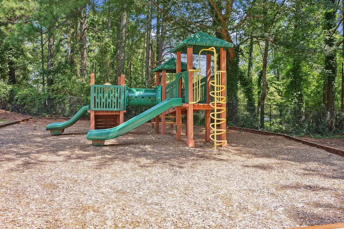 Inviting children's playground surrounded by lush greenery, featuring slides and a climbing structure for outdoor fun.
