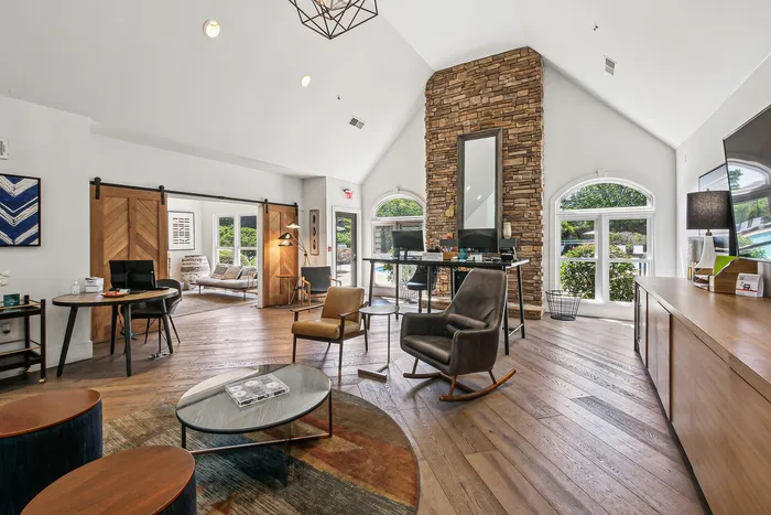 Bright and stylish open-plan living area featuring a cozy seating arrangement, modern furnishings, and an elegant stone accent wall.
