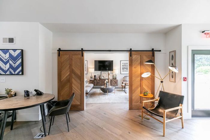 Elegant interior with modern sliding wood doors leading to a stylish living area, featuring chic furniture and contemporary decor.