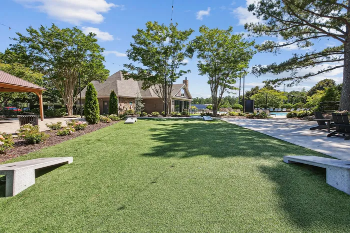 Charming outdoor area with lush green lawn, modern seating, and picturesque views surrounded by vibrant trees and a cozy building.