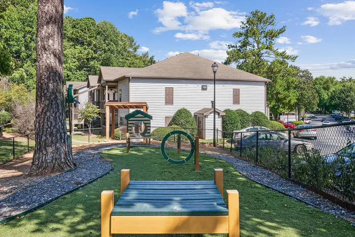 Charming family-friendly apartment complex with a well-maintained playground, surrounded by lush greenery and ample parking.