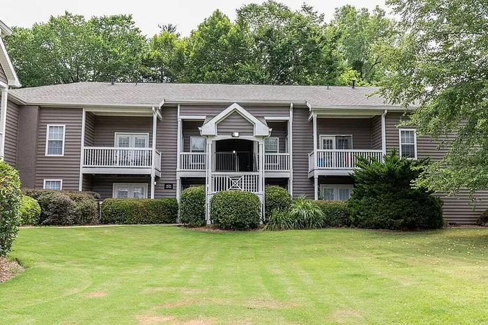 Charming apartment complex with manicured lawns, lush greenery, and inviting balconies.