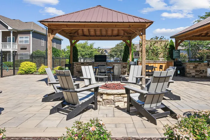 Inviting outdoor patio with cozy fire pit and elegant wooden gazebo, perfect for gatherings and relaxation.