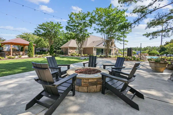 Charming outdoor space featuring a cozy fire pit surrounded by modern Adirondack chairs, lush greenery, and a stylish gazebo, perfect for relaxation.