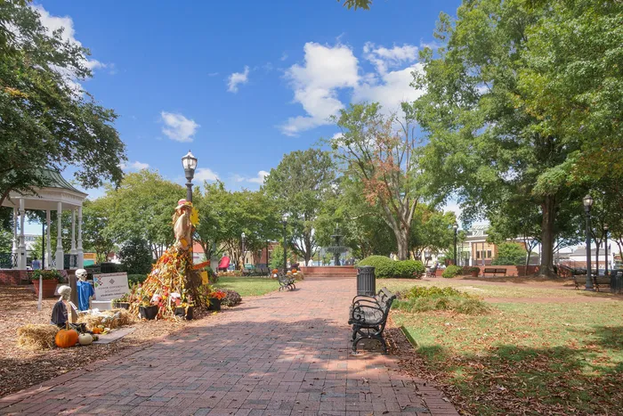 Charming park scene with festive autumn decorations, vibrant greenery, and cozy benches, perfect for a relaxing stroll.