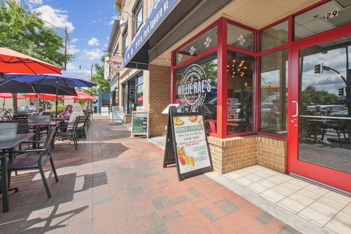Charming street view with a vibrant caf&eacute; offering inviting outdoor seating, colorful umbrellas, and a warm, welcoming atmosphere perfect for brunch enthusiasts.