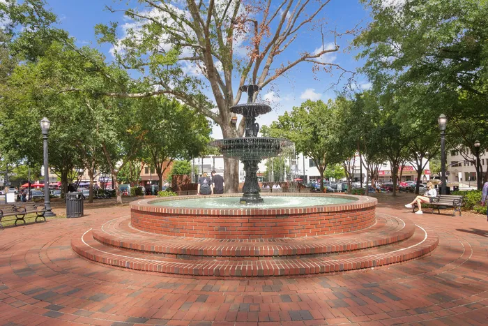 Charming city park with a beautiful multi-tiered fountain surrounded by lush trees and inviting benches.