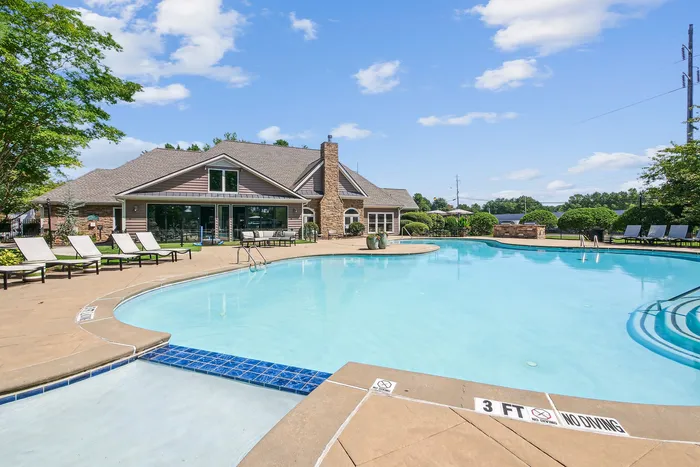 Inviting outdoor pool area with elegant lounge chairs and charming clubhouse in a serene setting.