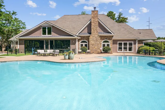 Charming suburban home with a refreshing pool, elegant stone chimney, and lush surroundings, perfect for relaxation and entertaining.