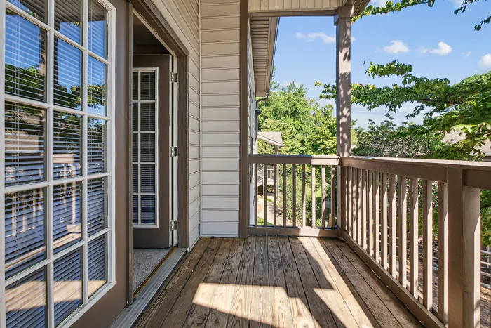 Inviting apartment balcony with wooden deck and views of lush greenery, perfect for relaxation.