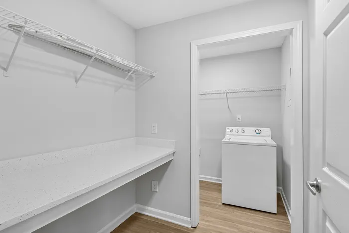 Modern laundry area with sleek white countertops and convenient washer setup, ideal for hassle-free living.