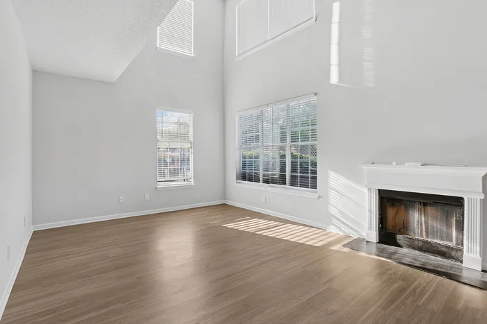 Bright and airy living room with large windows, elegant fireplace, and beautiful wood flooring.
