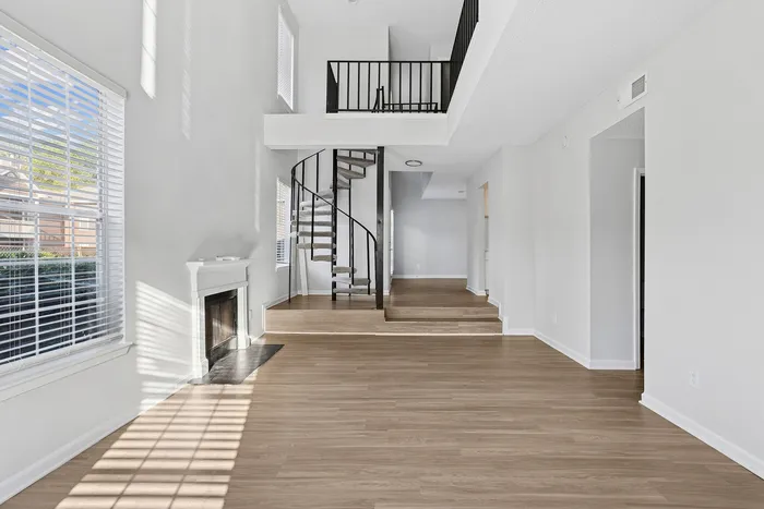 Elegant modern living space featuring expansive windows, a sleek spiral staircase, and stylish wood floors with abundant natural light.