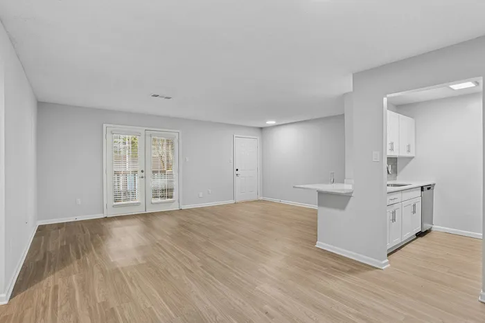 Bright and spacious open-plan living area with elegant wood flooring and modern kitchen, perfect for cozy gatherings.